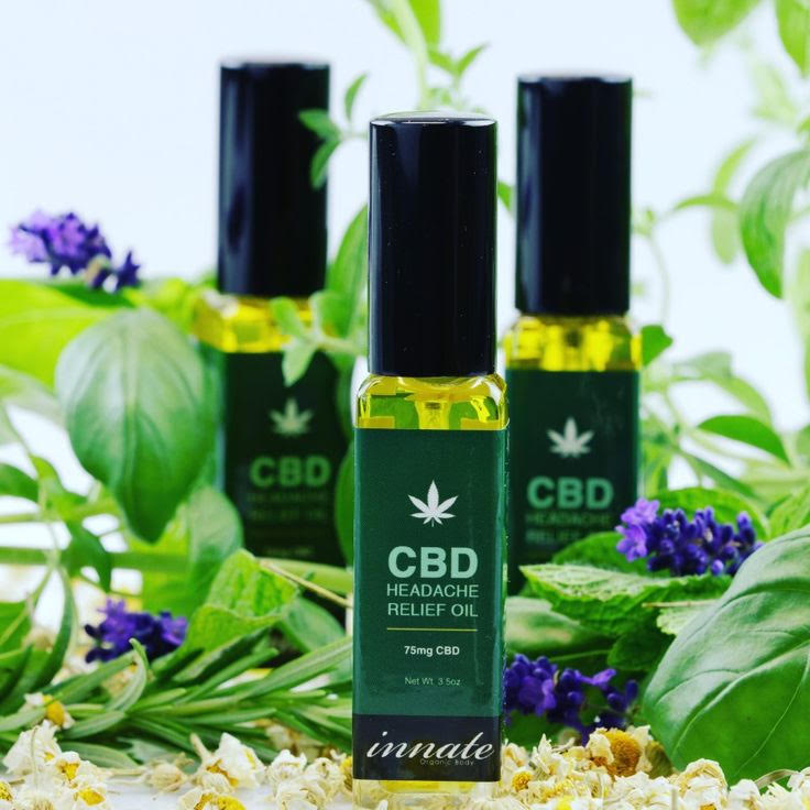 CBD headache relief oil bottles with green leaves and flowers in the background